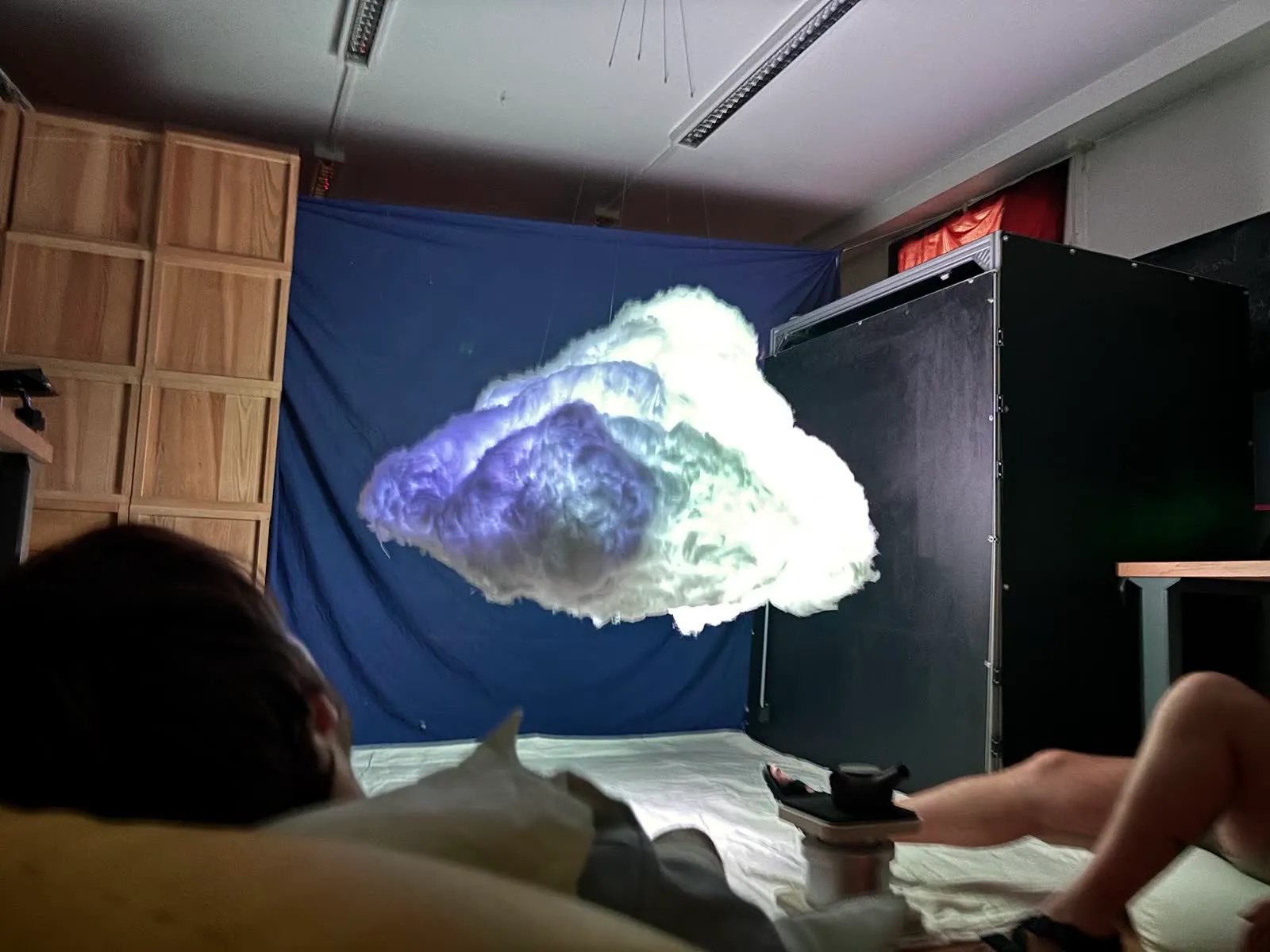 People lying on the floor beneath the cloud, lit blue