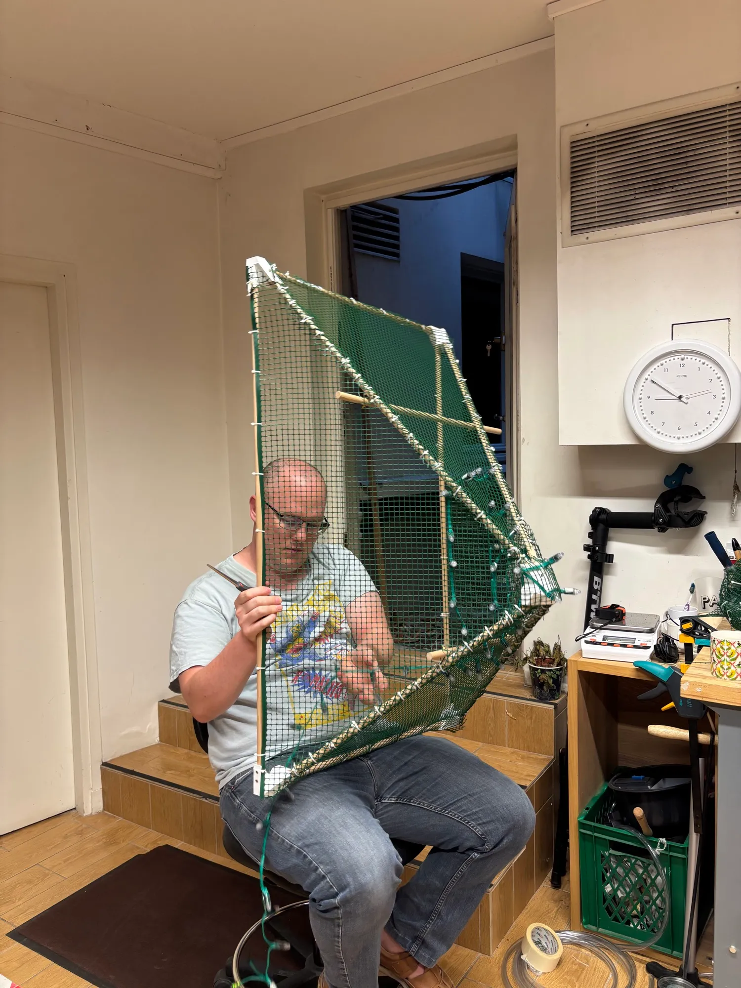 Michael weaving LED pixels onto one mesh-covered face of the pyramid frame.