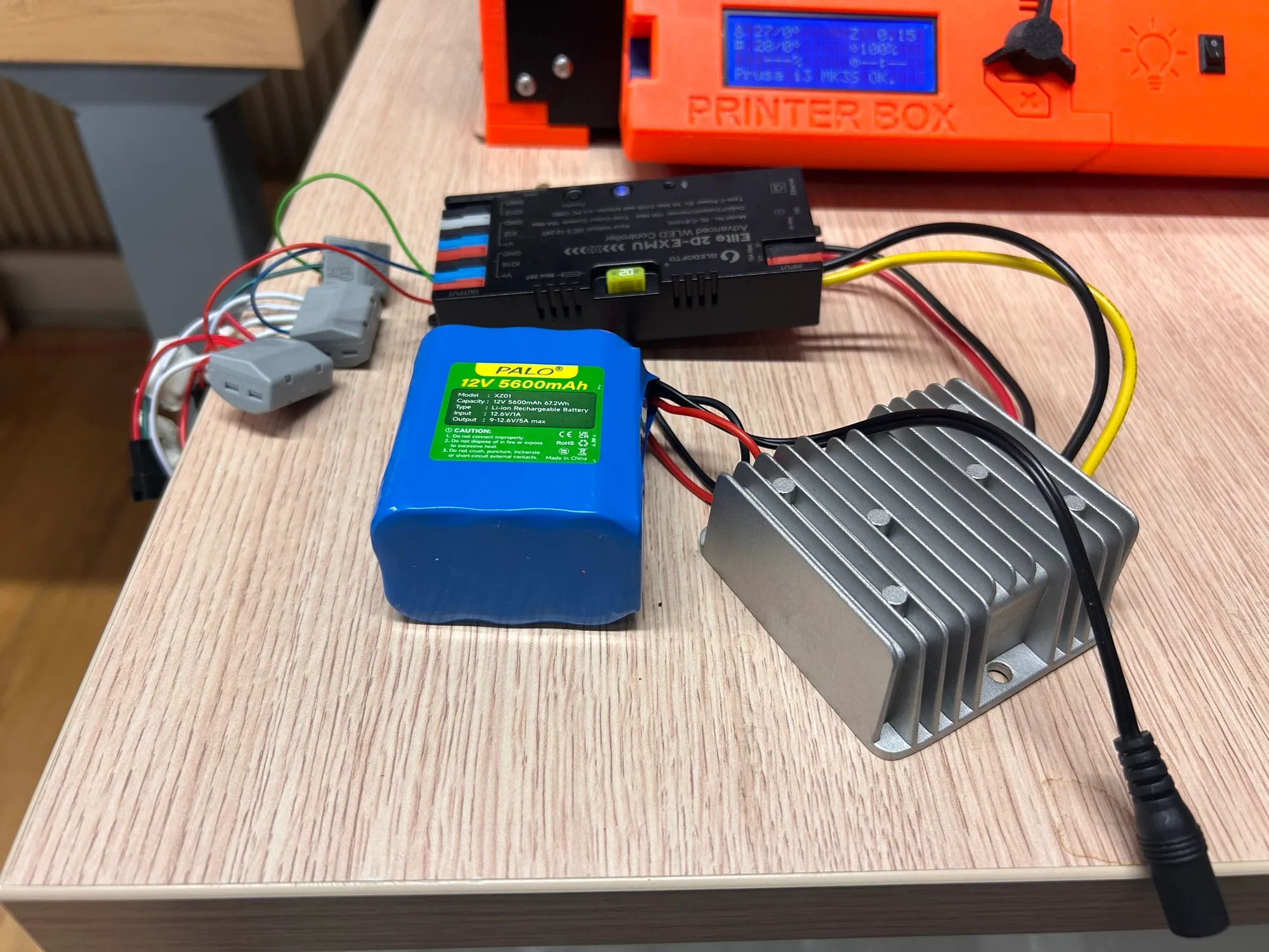 A new controller, a battery and a larger buck converter laid out on a desk.