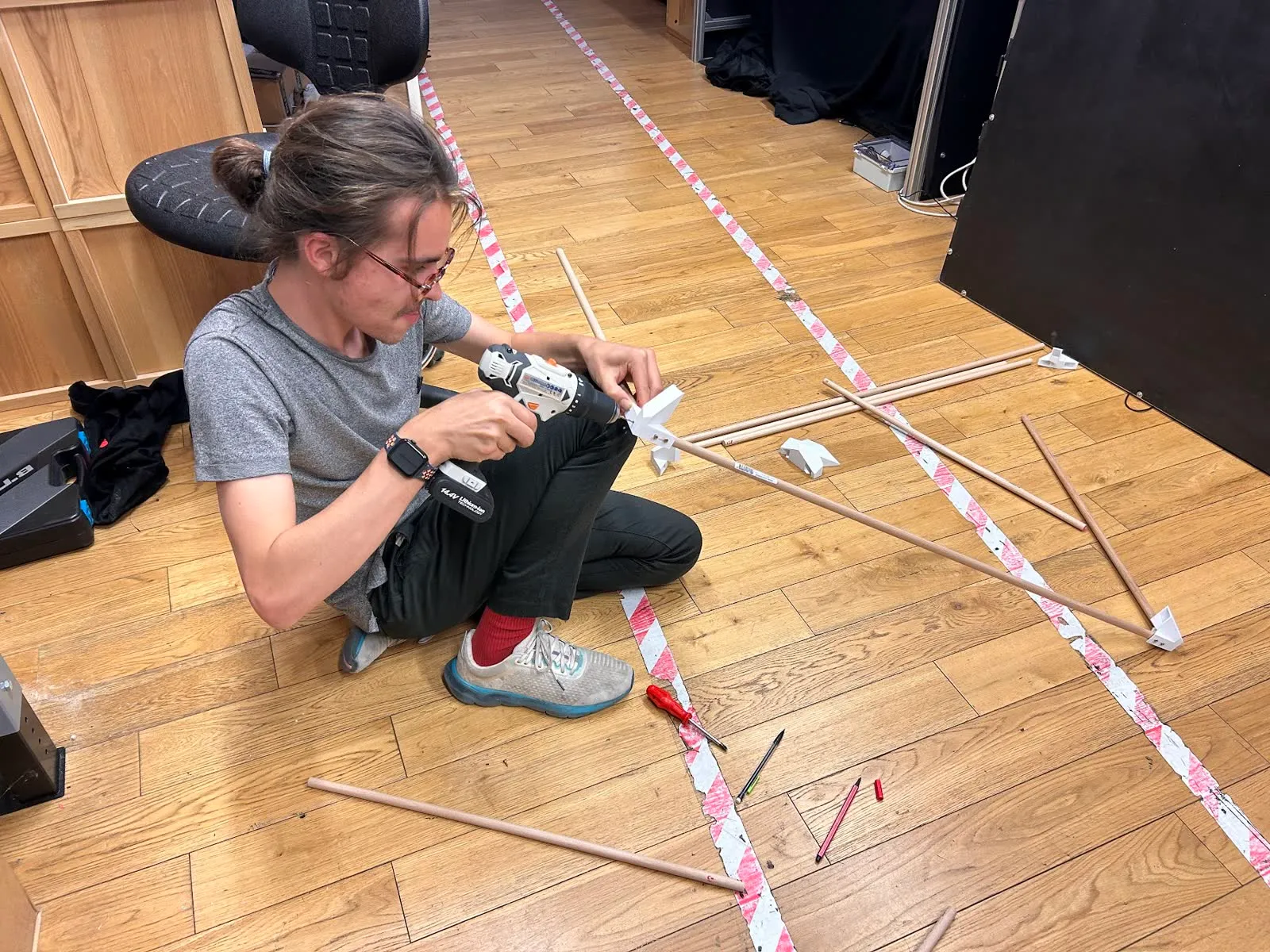 Wooden dowels and 3D-printed joints laid out on the workshop floor.