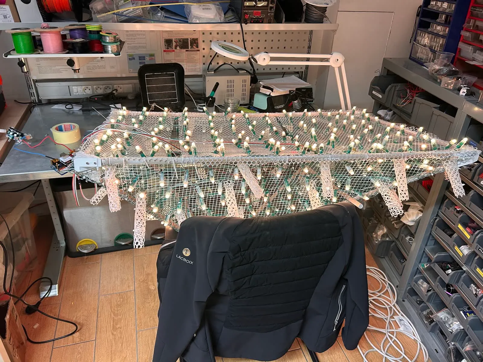 Rows of LED pixels lit up on white mesh, laid across a workbench