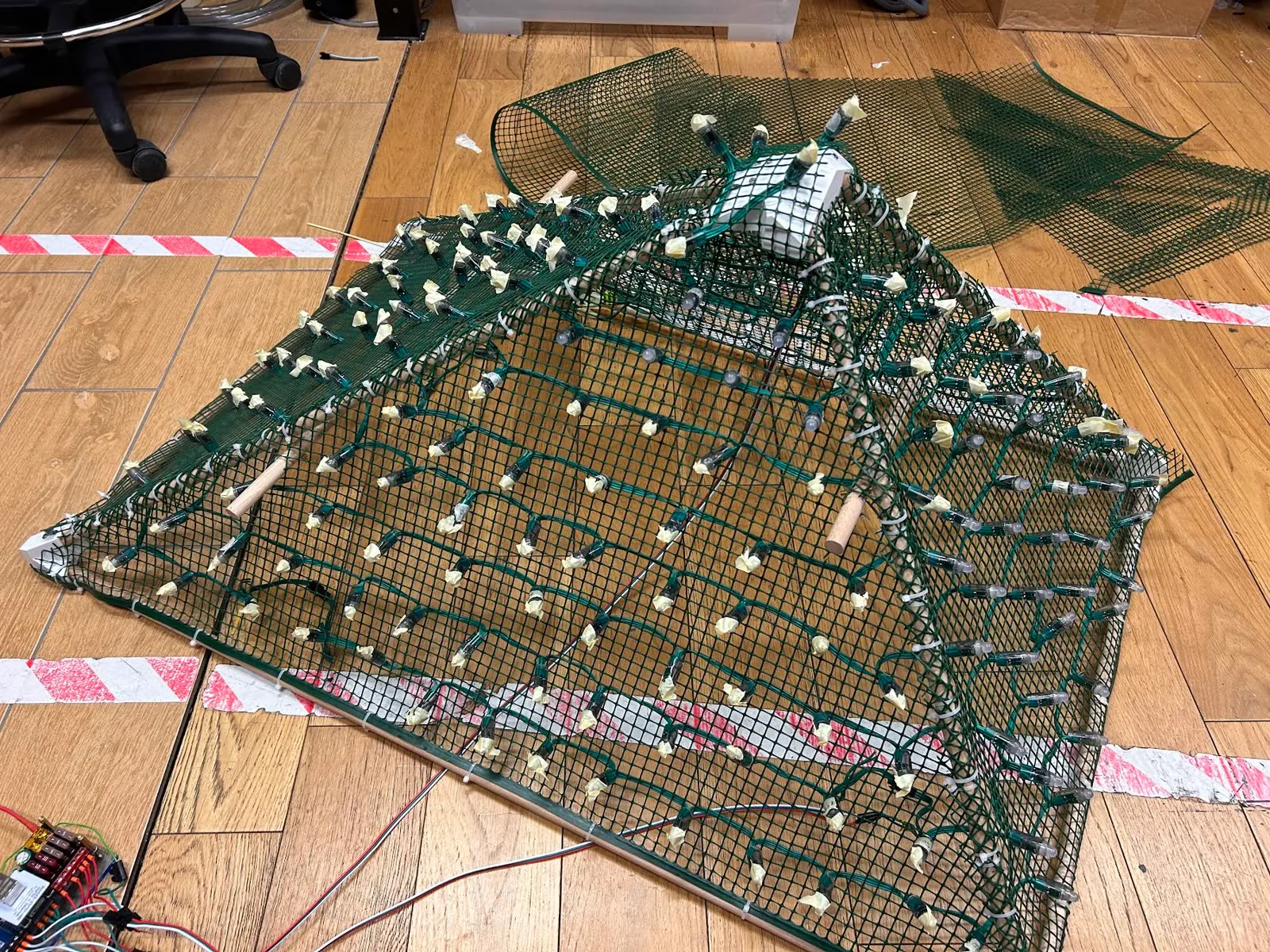 The mesh-wrapped pyramid on the workshop floor, with every LED pixel capped in masking tape.