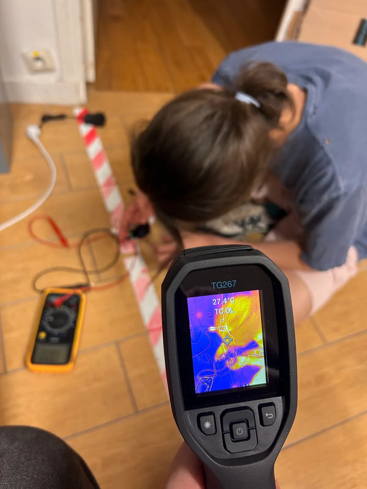 A thermal camera reading 27.4 °C, pointed at the wiring on the floor