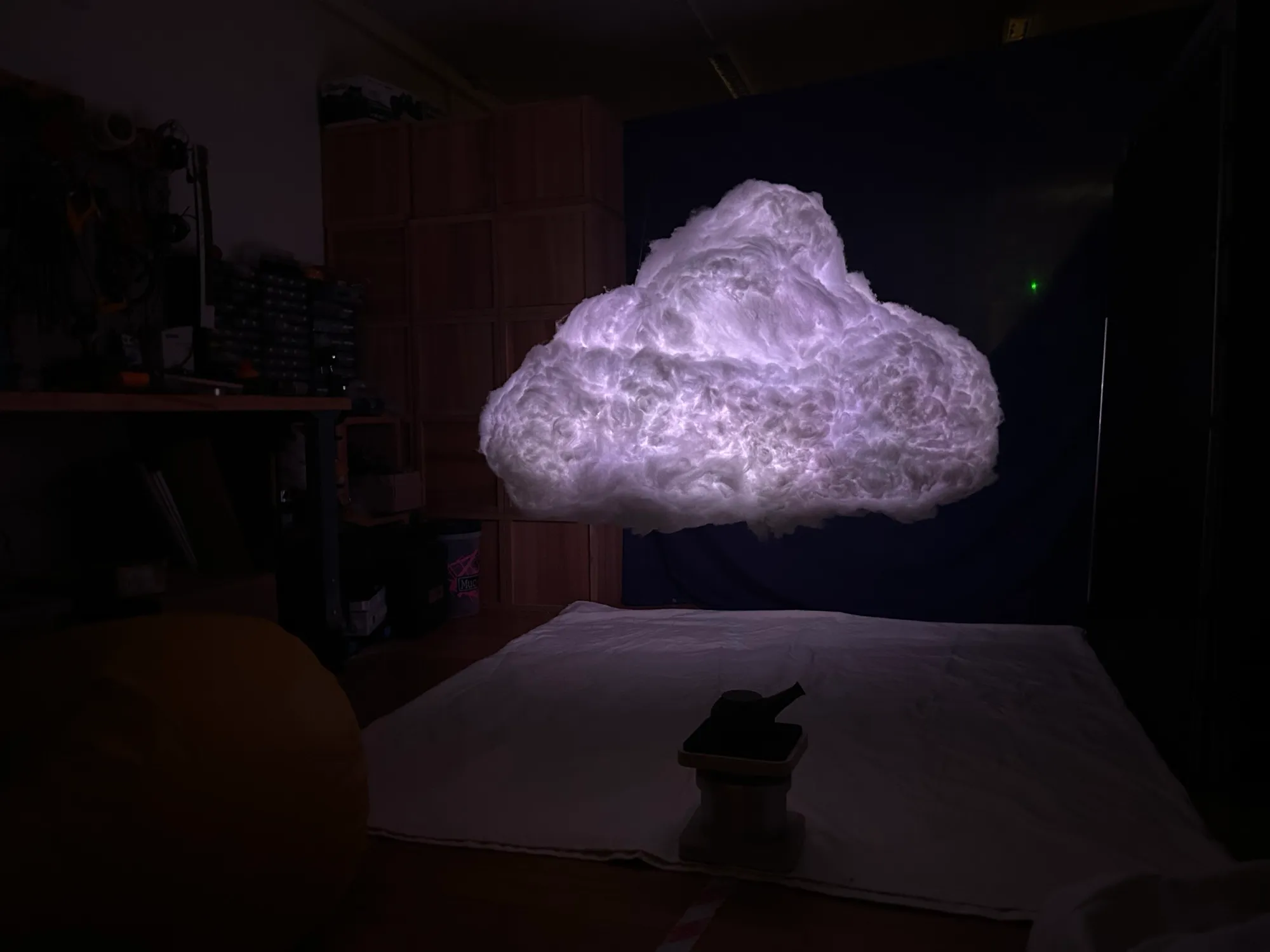 The pilot cloud glowing above white sheets, with a teapot on a small pedestal below.