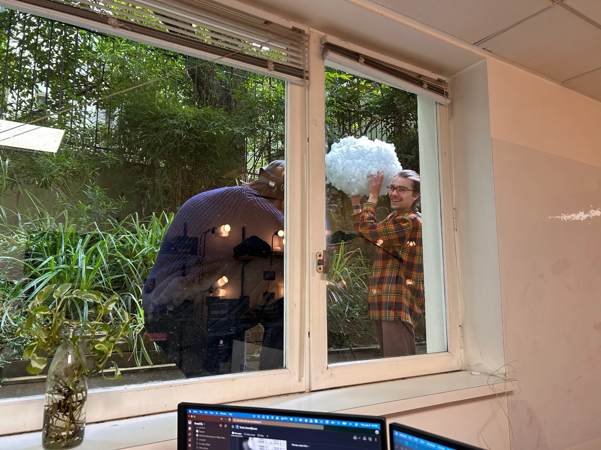 Seen through the studio window, Zéphir holds the cotton-covered cloud up in the garden while Michael photographs it.