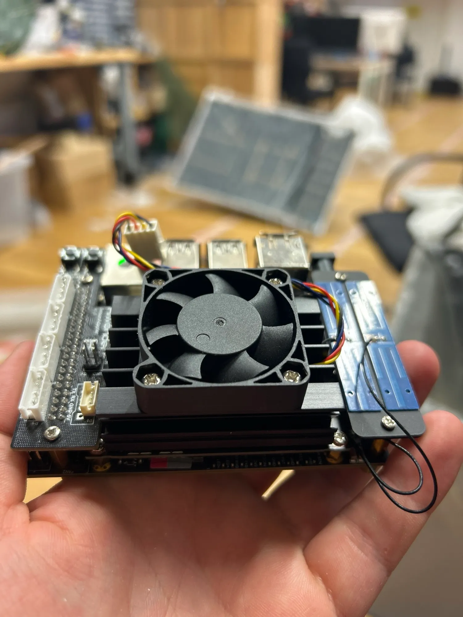 The electronics held in a hand, now with a small cooling fan mounted on top.