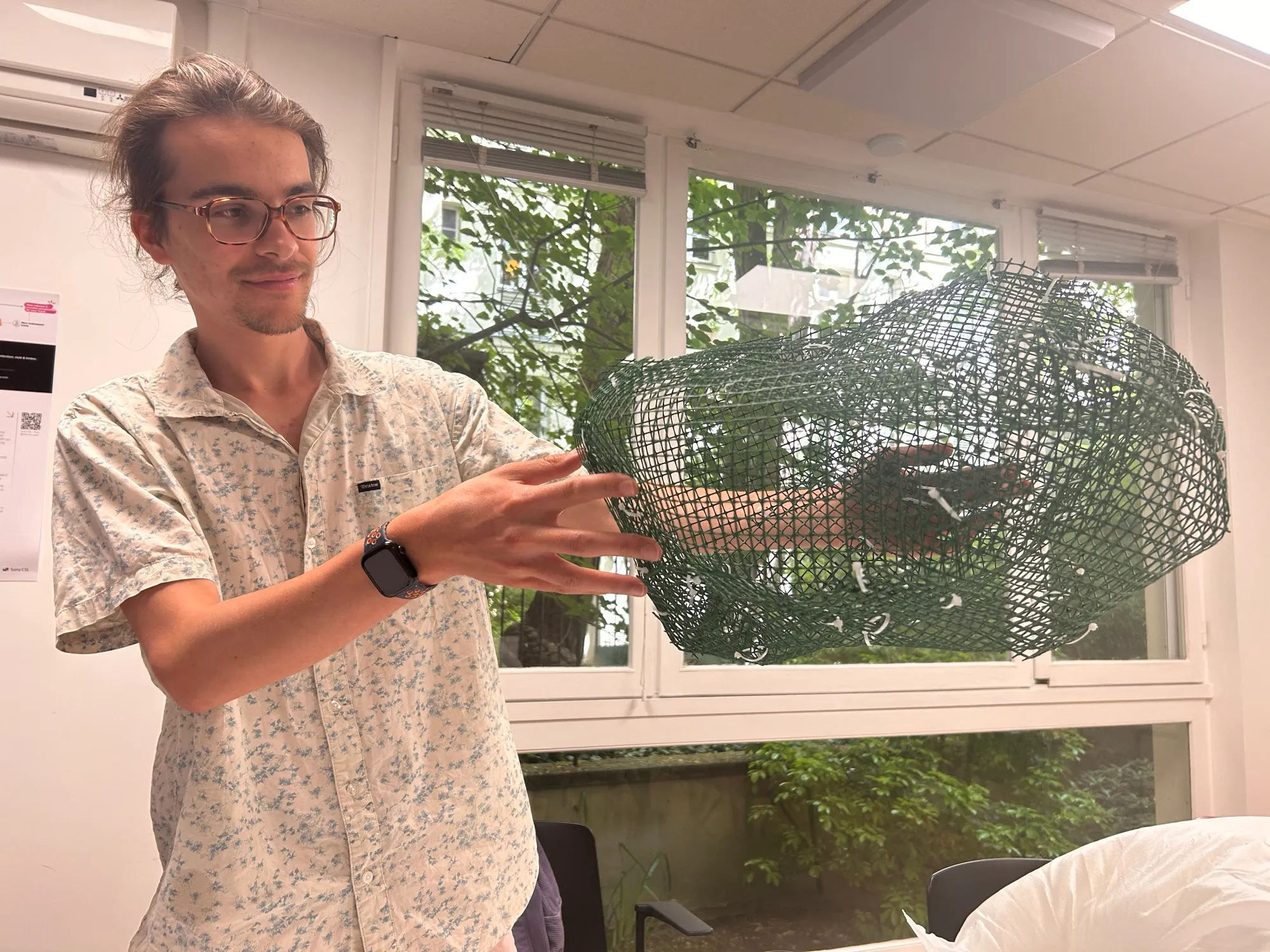 Zéphir holding up a rounded mesh form held together with zip ties.