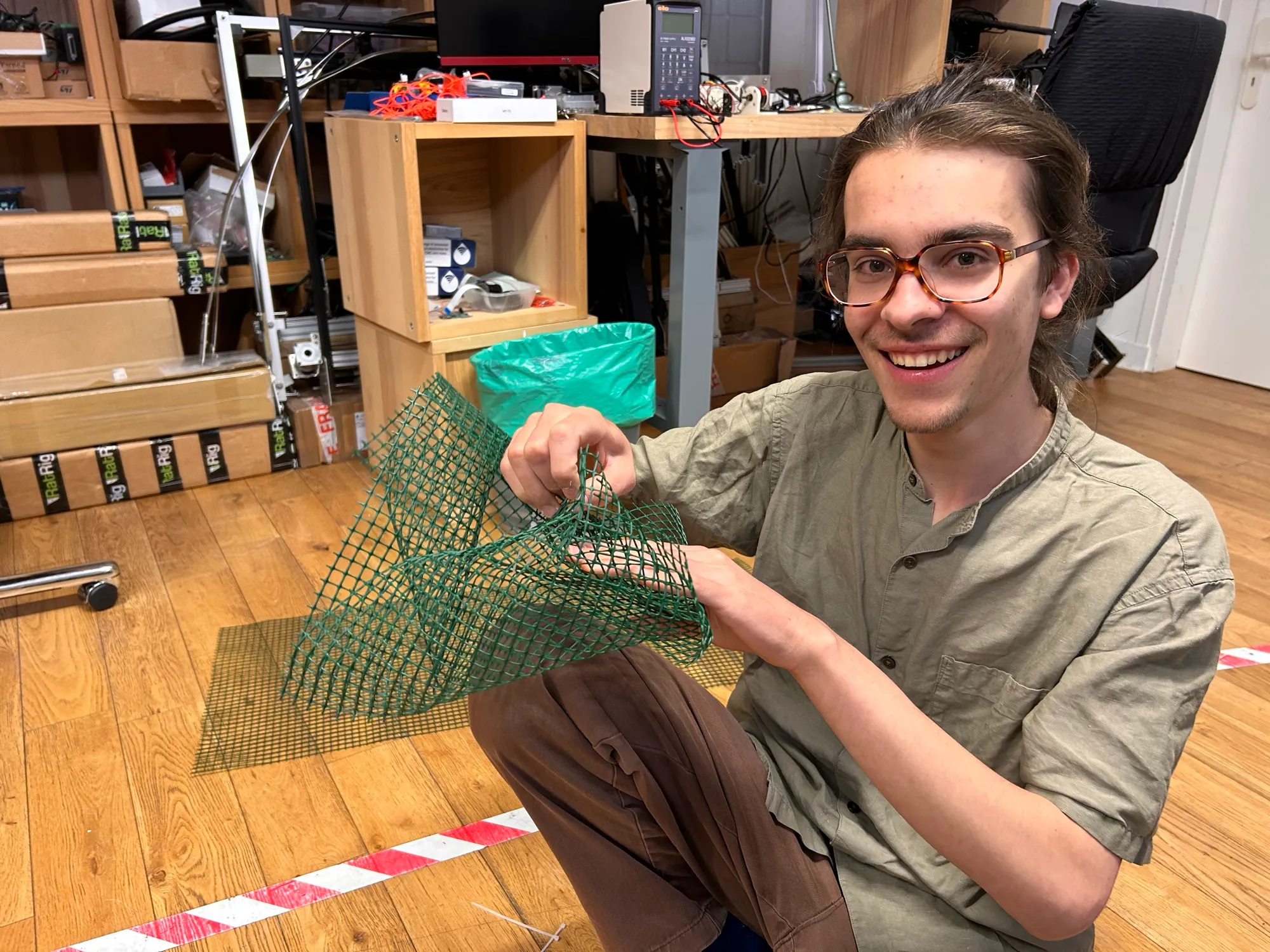 Zéphir bending a cut piece of green plastic mesh into a curve.