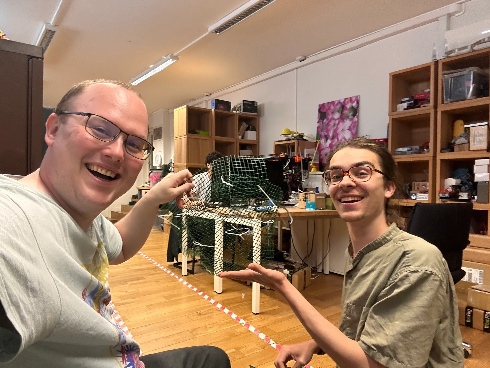 Michael and Zéphir grinning beside a mesh form draped over a small table.