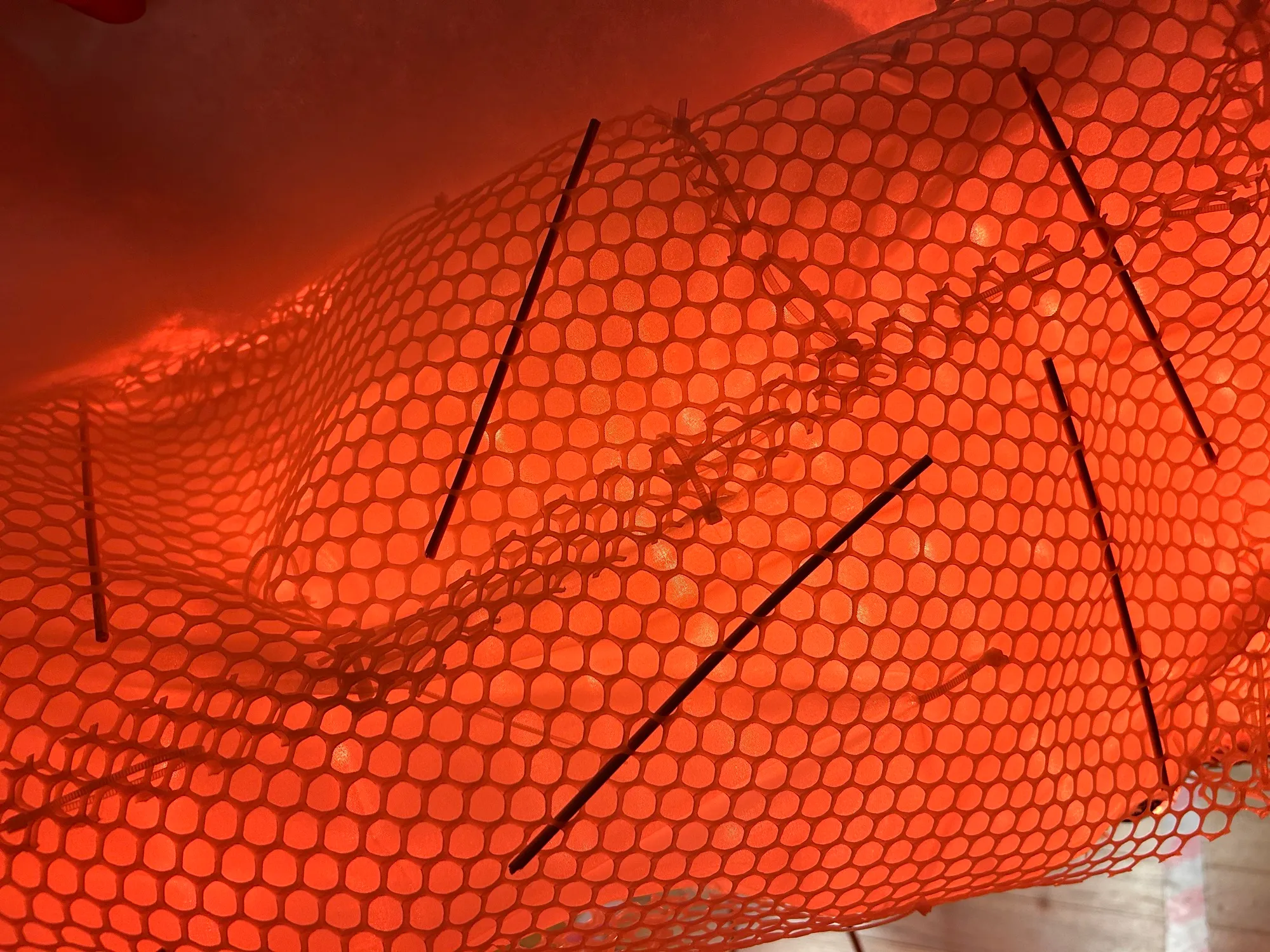 Close-up of the diffuser under the hexagonal mesh, glowing orange, with bamboo skewers through it.