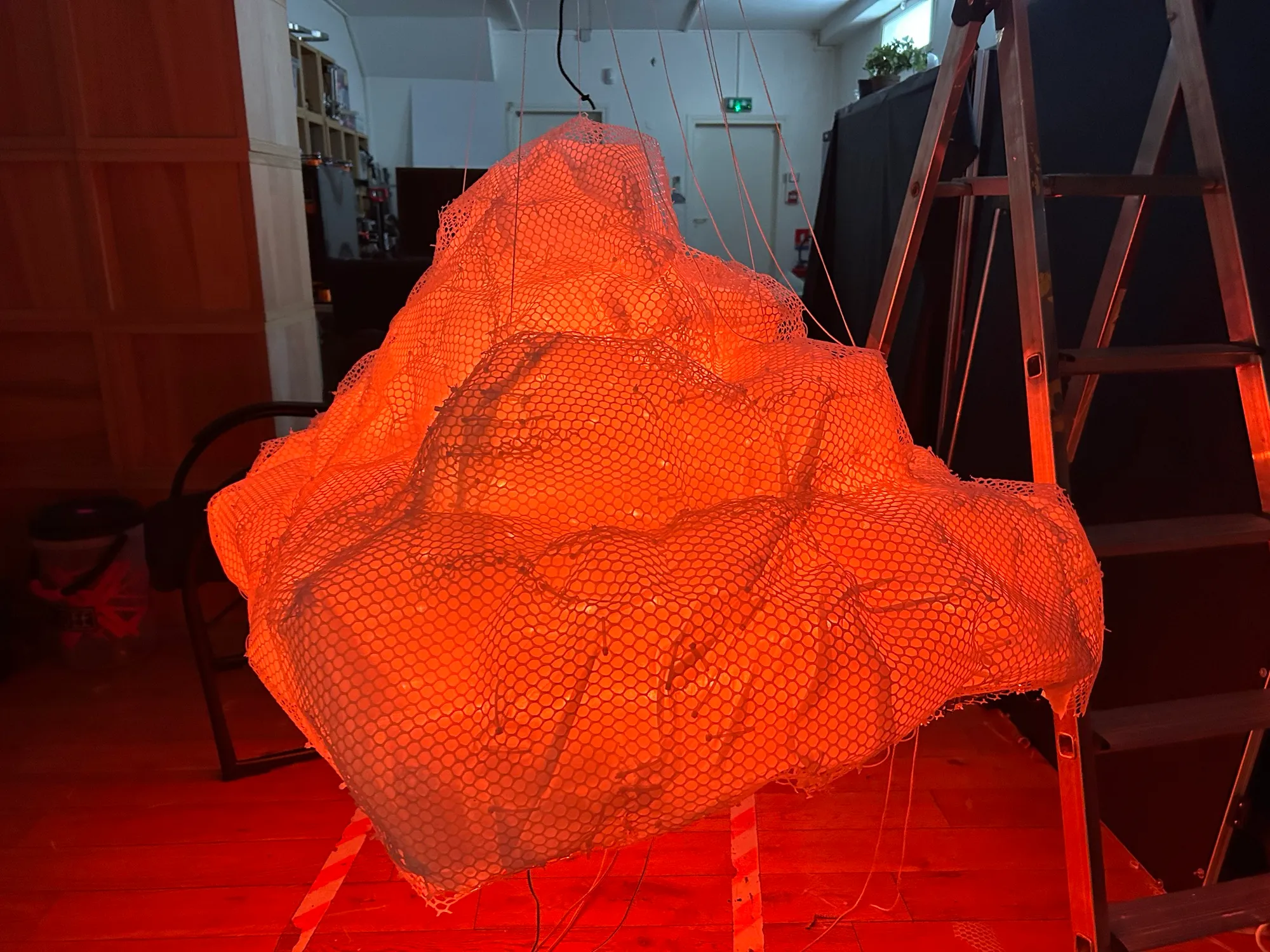 The frame draped only in the nylon diffuser, glowing orange in the workshop.