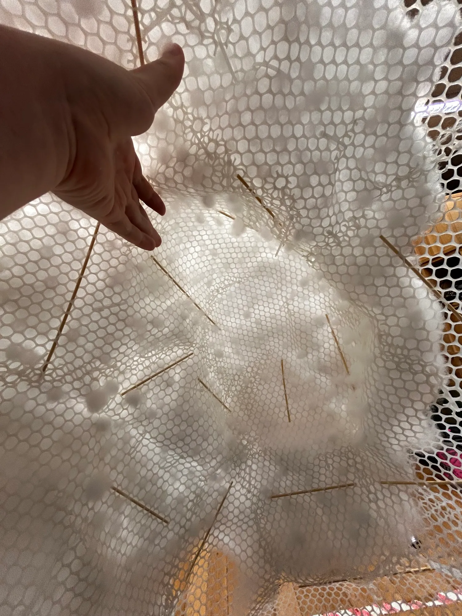 Shaping the white hexagonal mesh of the outer layer by hand.