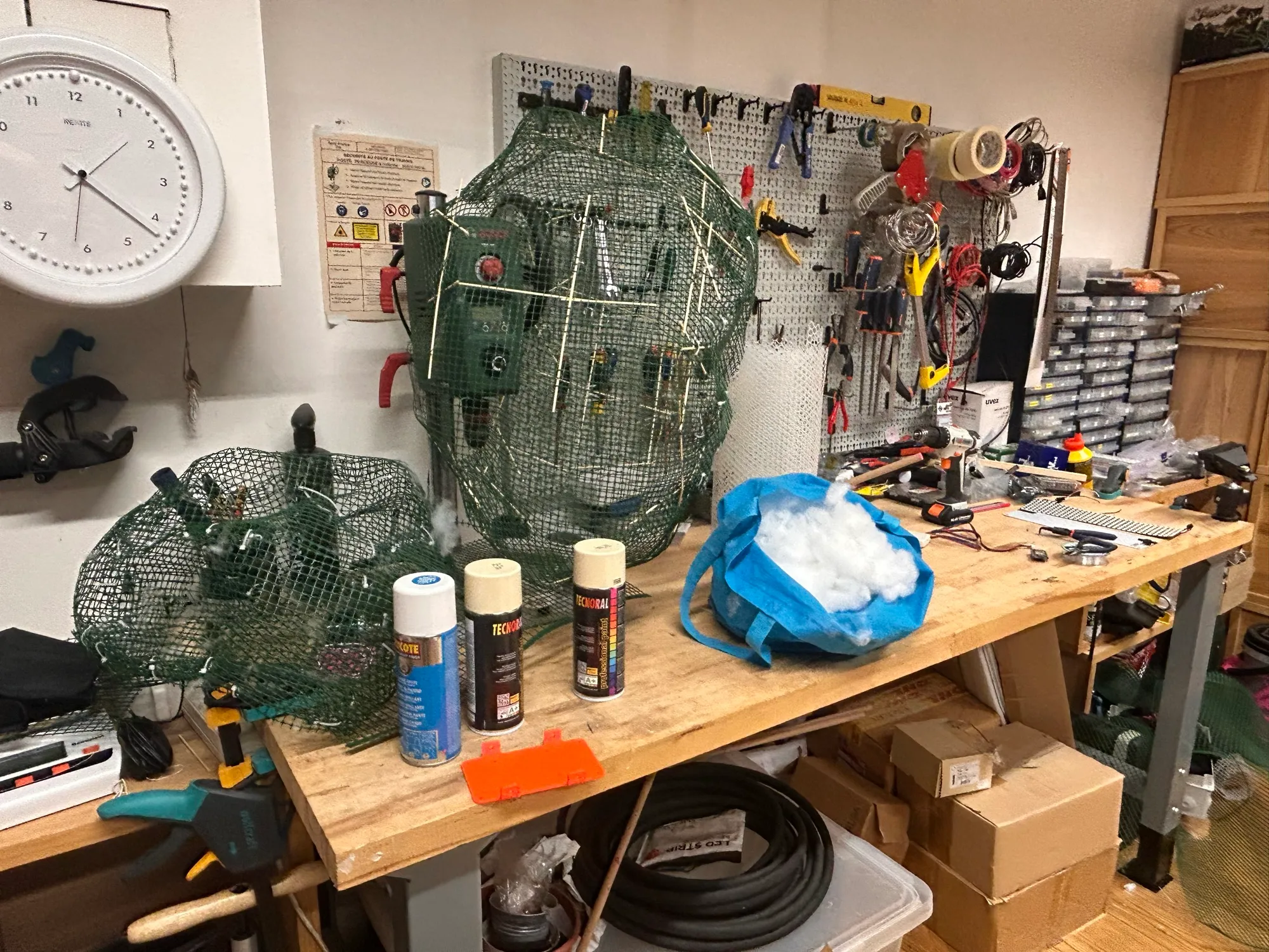 The workbench covered in mesh, fibre, spray cans and tools.