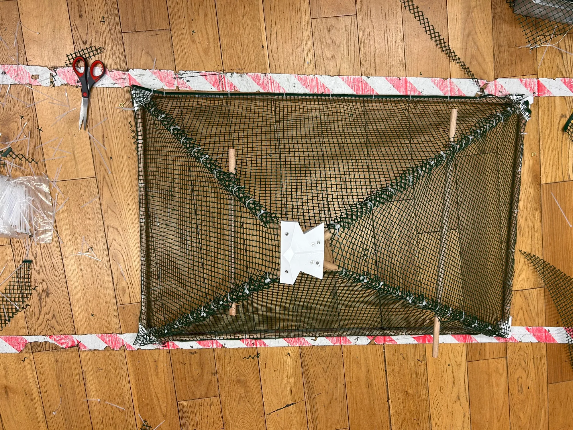 The completed pyramid frame wrapped in green plastic mesh with support struts visible.