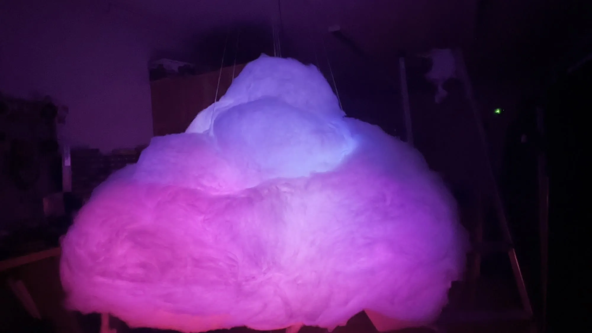 The cloud flaring magenta and violet in a dark workshop as a sprite passes through it.