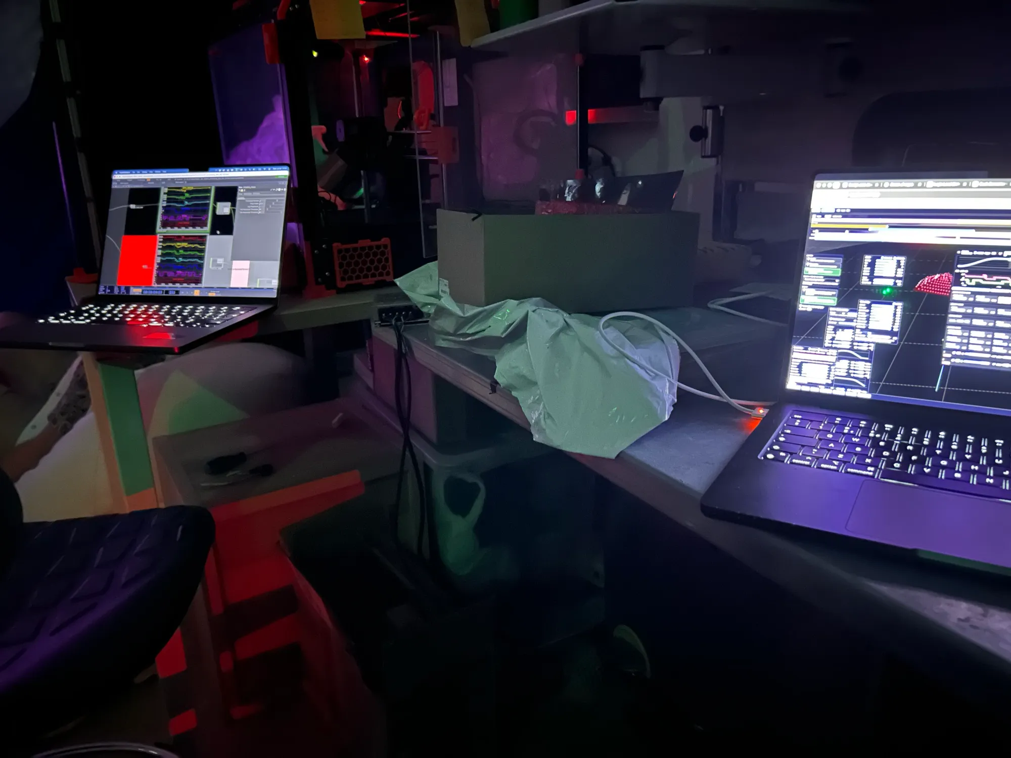 Two laptops side by side at the edge of the room, with the cloud lit in the background.
